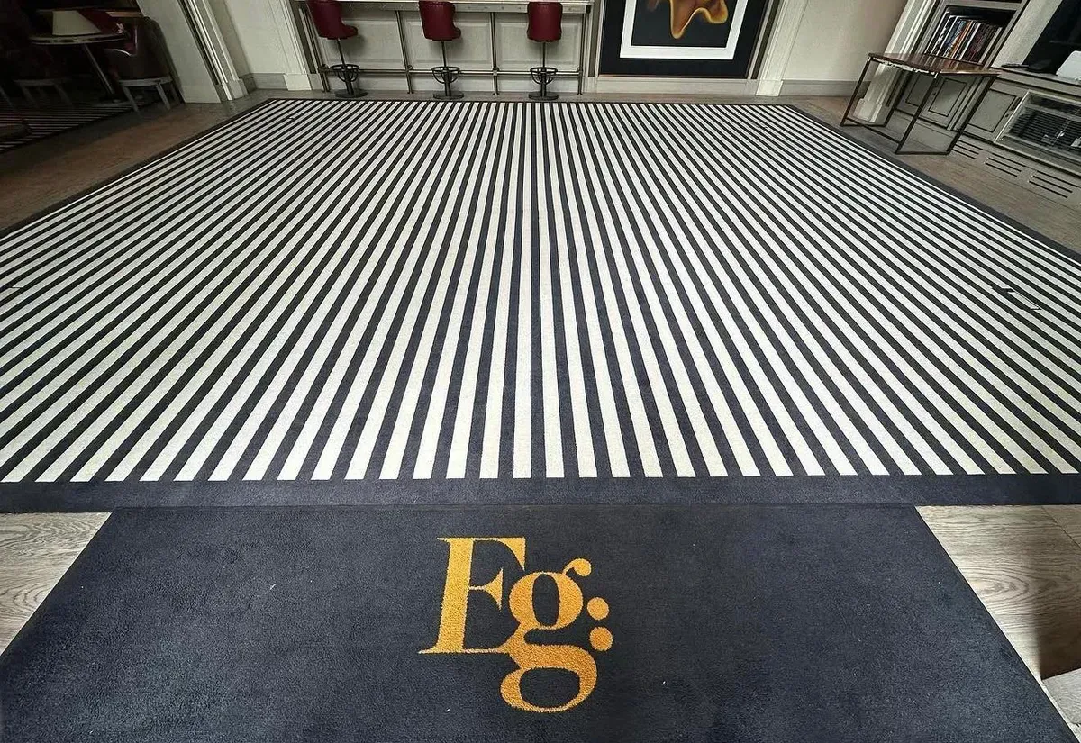 Bespoke black-and-white striped carpet with a custom logo entrance mat in a bar